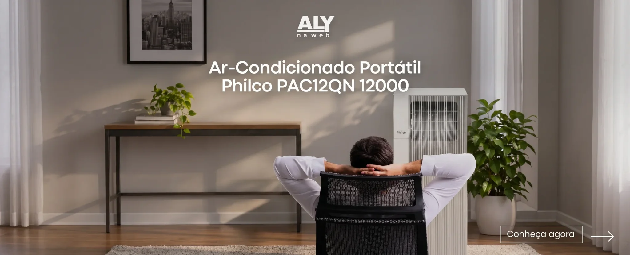 Man relaxing in an office chair in front of a white Philco PAC12QN 12000 portable air conditioner.